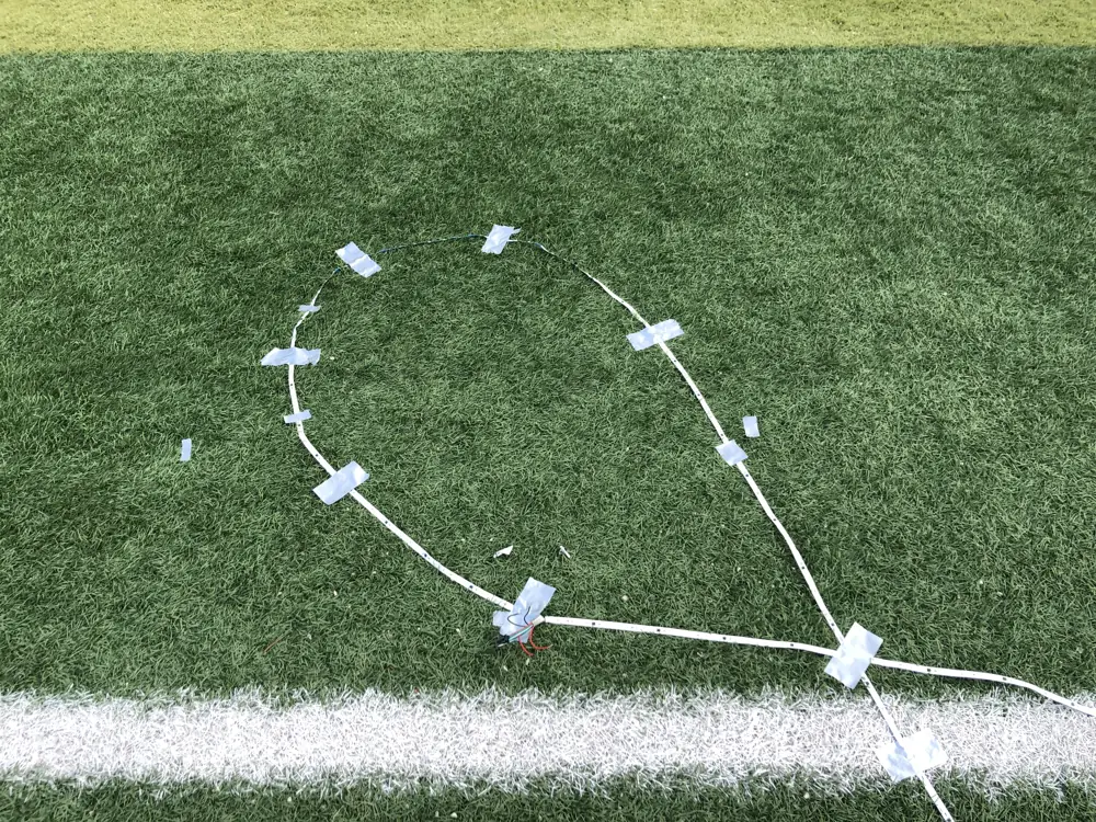 LED strip taped out in a looping figure on the artificial turf of the sports ground