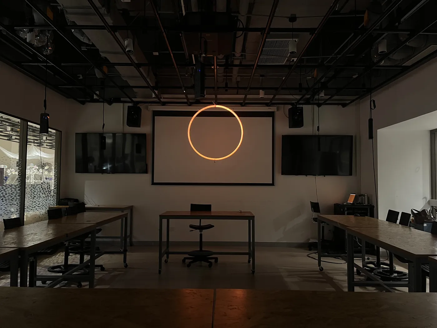 The LED ring hanging in a darkened classroom set up for the Interaction Lab final show