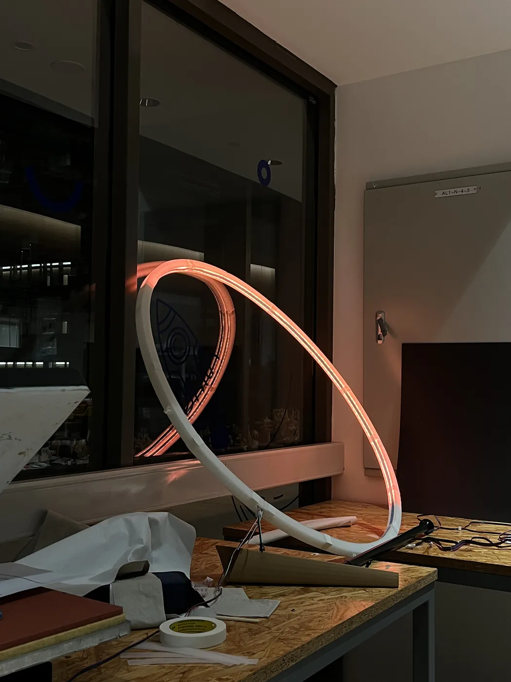 A ring of orange LED light leaning against a window on a cluttered lab workbench